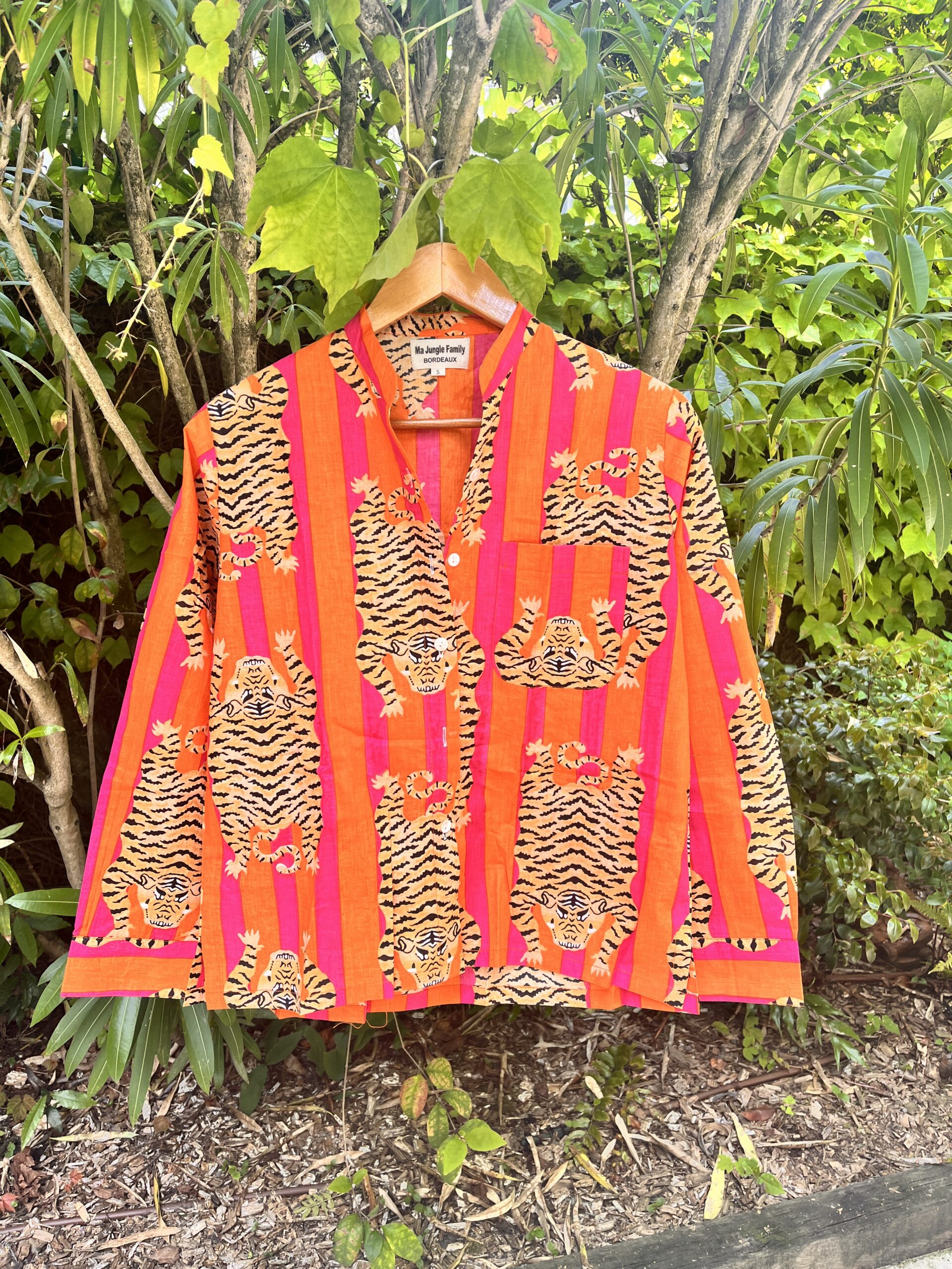 Cet ensemble unique associe le charme de l’artisanat indien et le savoir-faire de notre atelier bordelais. La chemise à col Mao, élégamment boutonnée avec de sublimes boutons en nacre, est imprimée à la main selon la technique ancestrale du block print en Inde. Le short assorti reprend les mêmes imprimés et se distingue par ses finitions soignées : poches latérales et arrières, petits boutons délicats sur les côtés, cuisses en nacre… chaque détail compte. Un look à la fois décontracté et raffiné, pensé pour celles qui aiment porter des pièces uniques, responsables et empreintes de voyage. Créé avec amour à Bordeaux, fabriqué à la main entre ici et ailleurs. Imprimé blockprint Frida Kahlo rose orange rose rayé et tigres