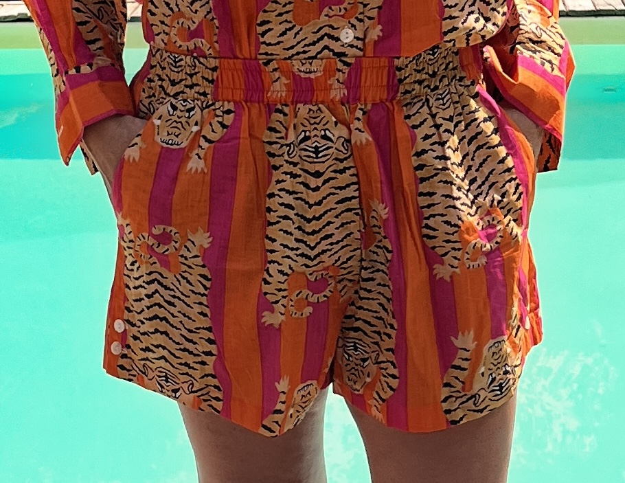Cet ensemble unique associe le charme de l’artisanat indien et le savoir-faire de notre atelier bordelais. La chemise à col Mao, élégamment boutonnée avec de sublimes boutons en nacre, est imprimée à la main selon la technique ancestrale du block print en Inde. Le short assorti reprend les mêmes imprimés et se distingue par ses finitions soignées : poches latérales et arrières, petits boutons délicats sur les côtés, cuisses en nacre… chaque détail compte. Un look à la fois décontracté et raffiné, pensé pour celles qui aiment porter des pièces uniques, responsables et empreintes de voyage. Créé avec amour à Bordeaux, fabriqué à la main entre ici et ailleurs. Tissu fleuri vert et rose, tigre orange