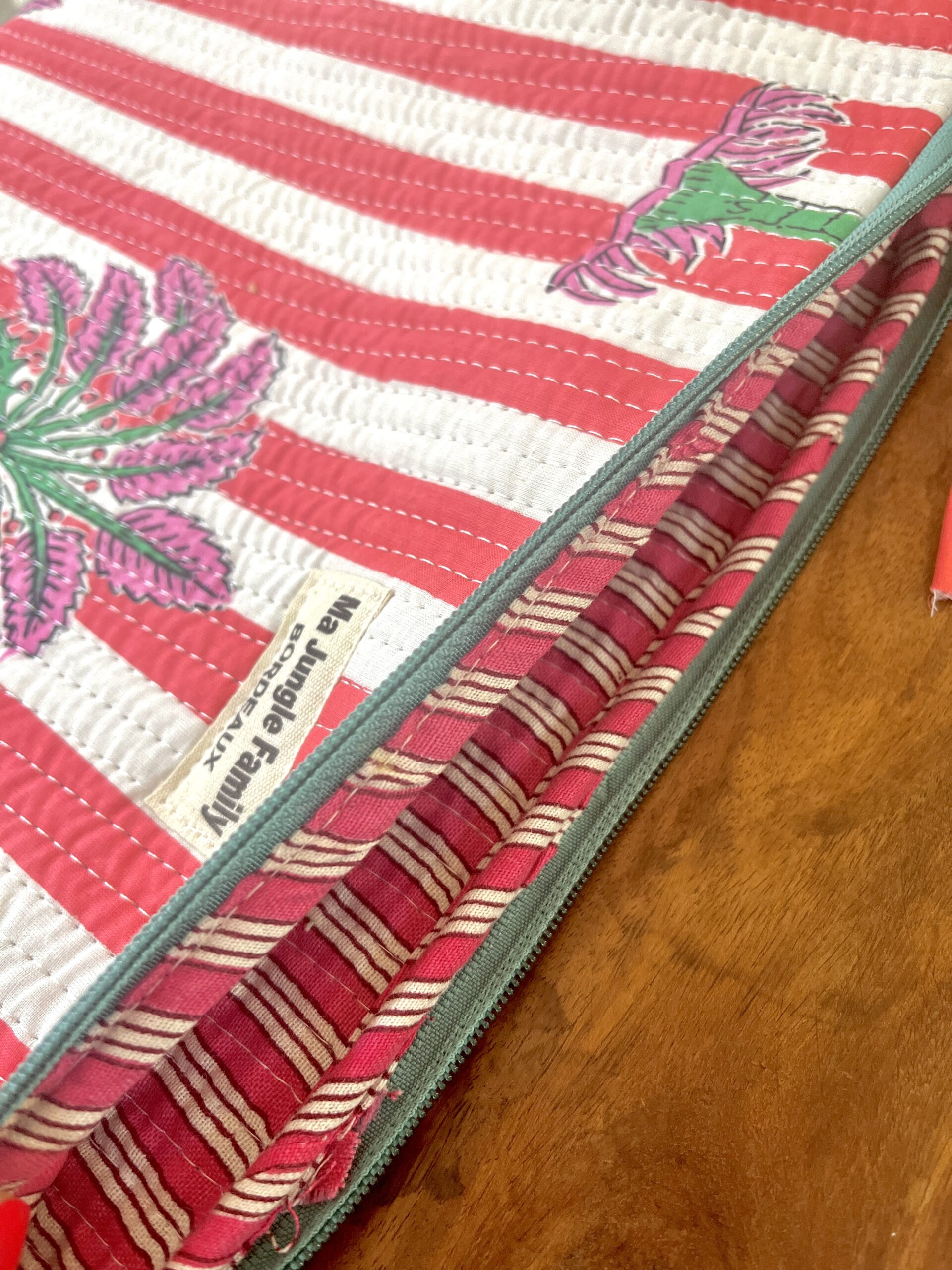 Housse d’ordinateur en coton indien matelassé avec imprimé floral block-print, format 15 pouces, faite main. Housse d’ordinateur artisanale en coton indien, motif original, utilisée pour transporter un laptop, Accessoire éthique : housse ordinateur bohème en coton imprimé, tenue à la main dans un décor naturel. Housse d’ordinateur Ma Jungle Family – coton indien artisanal – Bordeaux Fleuriste colorés hibiscus vert et orange, rouge palmier
