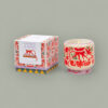 Bougie artisanale Monkey en céramique peinte à la main, motif singe rouge orangé, posée sur une table en bois avec une couverture en laine beige pour une ambiance cocooning et chaleureuse. Boîte décoration, adopo, paddywax, jungle