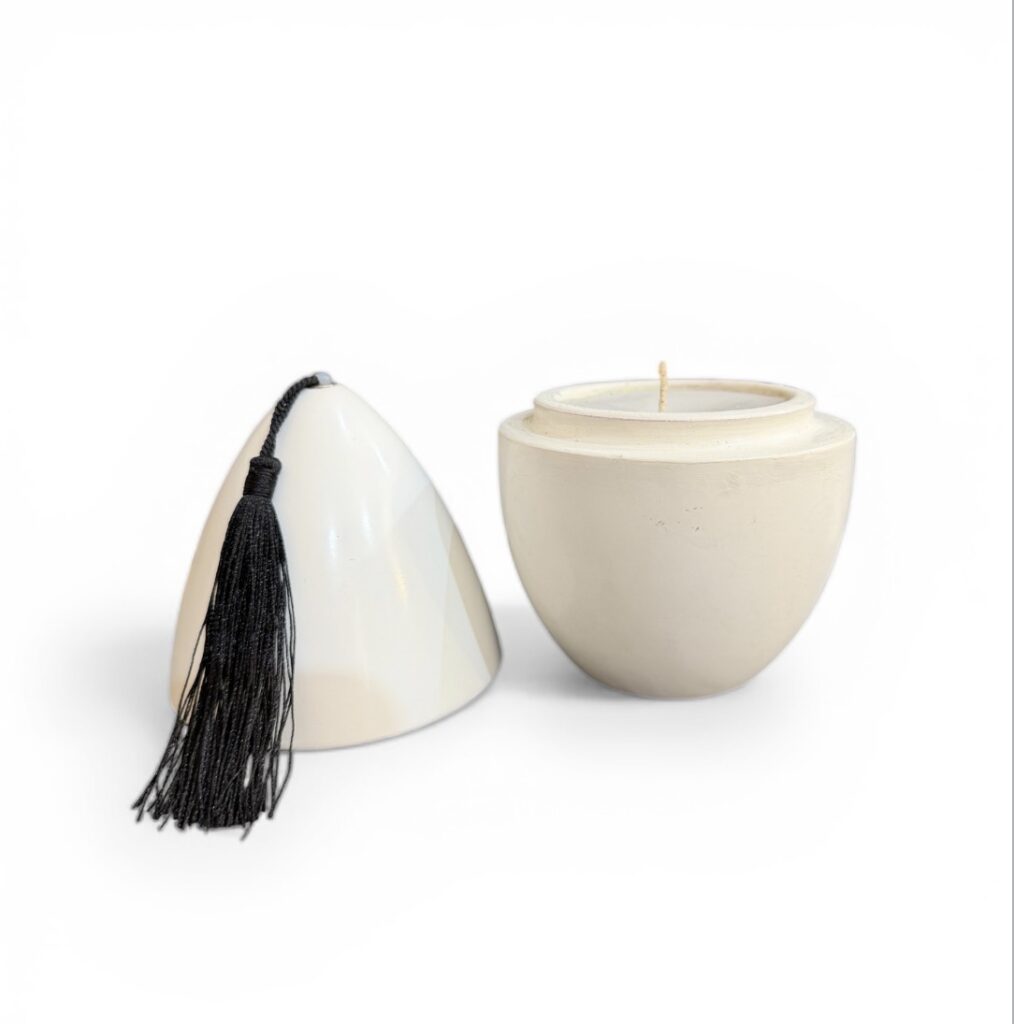 Bougie artisanale en terre cuite en forme d’œuf, fabriquée à la main au Maroc, objet décoratif aux finitions naturelles. Détail de bougie en terre cuite façonnée à la main, texture brute et nuances naturelles, artisanat du Maroc. Bougie artisanale en terre cuite bleu majorelle, Marrakech, Yves saint Laurent, faite main au Maroc, objet déco unique et authentique. Ma Jungle Family, Tadelakt écru, pompon noir