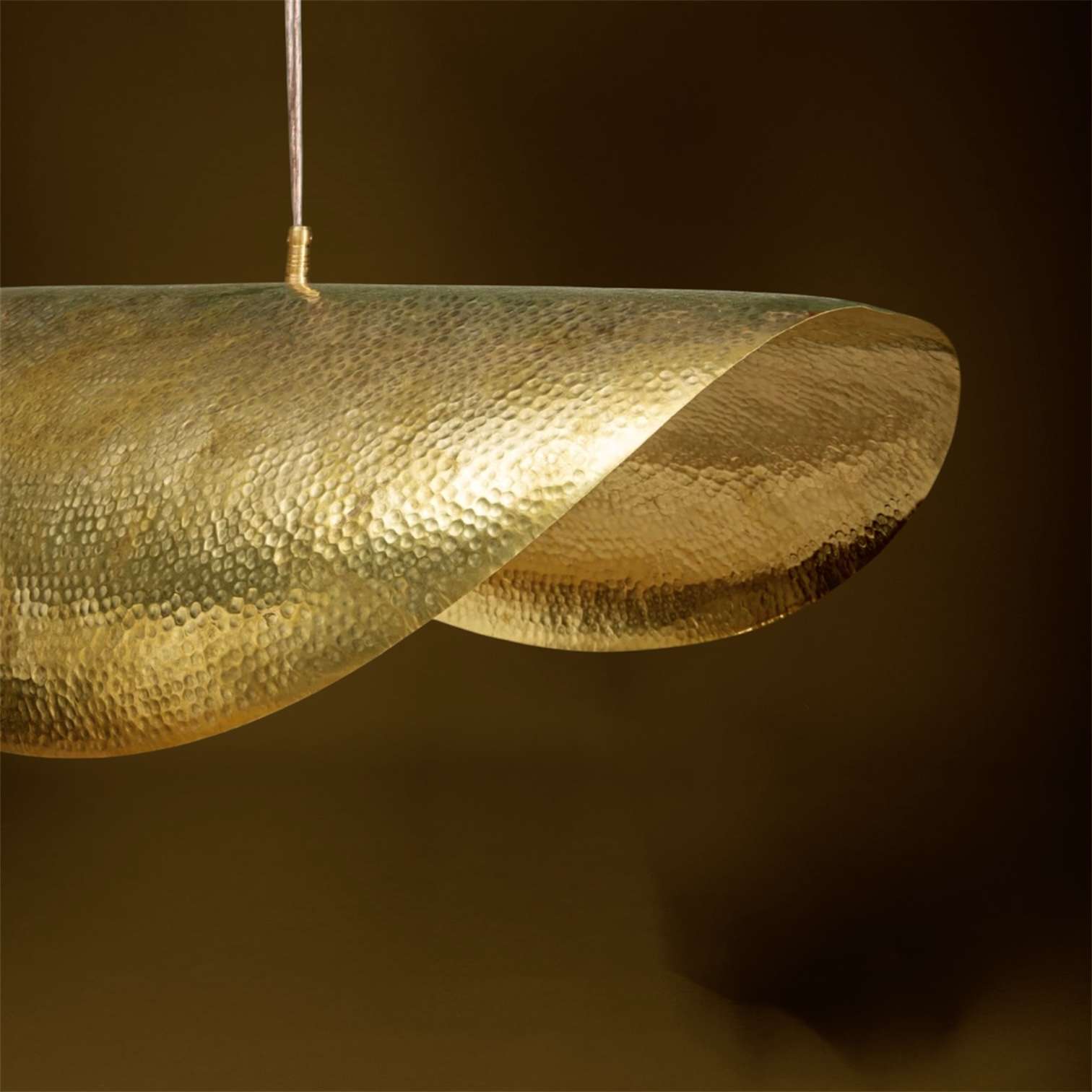 Suspension artisanale en laiton martelé fabriquée au Maroc. Sa forme incurvée et sculpturale mesure 80 cm de diamètre et crée une lumière chaleureuse et élégante.