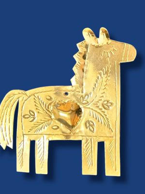 Cheval décoratif en laiton gravé à la main, suspendu sur un mur blanc, mettant en valeur les motifs artisanaux marocains