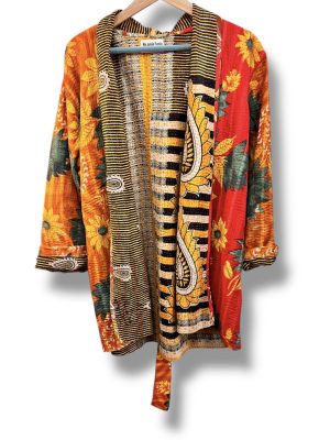 Veste kantha vintage réversible en coton recyclé, faite main à partir de saris indiens – pièce unique aux motifs fleuris colorés, exposée sur un portant. Rouge, vert, fleurs, orange, reversilble