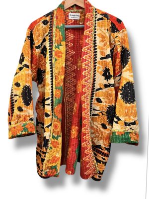 Veste kantha vintage réversible en coton recyclé, faite main à partir de saris indiens – pièce unique aux motifs fleuris colorés, exposée sur un portant. Rouge, vert, fleurs, orange, reversilble